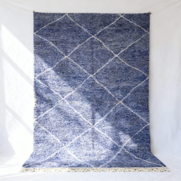 Handwoven sky blue farmhouse rug with white diamond lattice pattern hanging on white wall