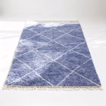 Blue diamond pattern farmhouse rug with geometric white lines and natural fringe tassels on neutral background