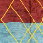 Close-up texture of handspun wool on multicolor Moroccan rug showing burgundy and blue sections