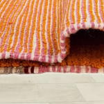 Detail view of geometric black pattern on bright orange authentic Moroccan rug