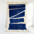 Handmade Moroccan beni rug with navy blue geometric pattern and cream fringe on white background