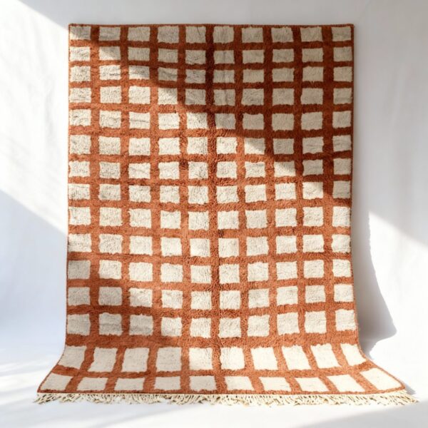 Terracotta and ivory handmade Moroccan trellis rug with geometric grid pattern on white wall