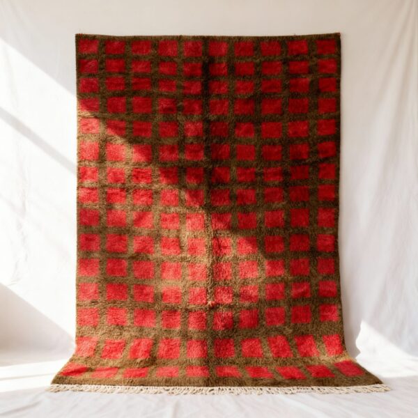 Red and brown handmade Moroccan trellis rug with geometric grid pattern hanging on white wall