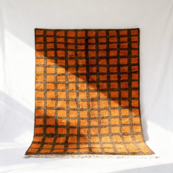 Handwoven Moroccan trellis rug with orange and brown grid pattern on white background