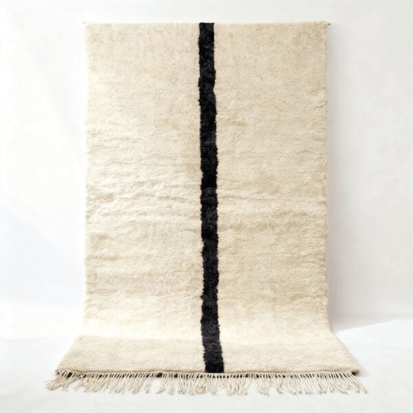 Traditional Moroccan rug handwoven in cream wool with bold black vertical stripe, featuring plush Beni Ourain style