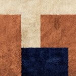 Reverse angle of modern boho rug showing navy terracotta geometric blocks on cream handwoven cotton base