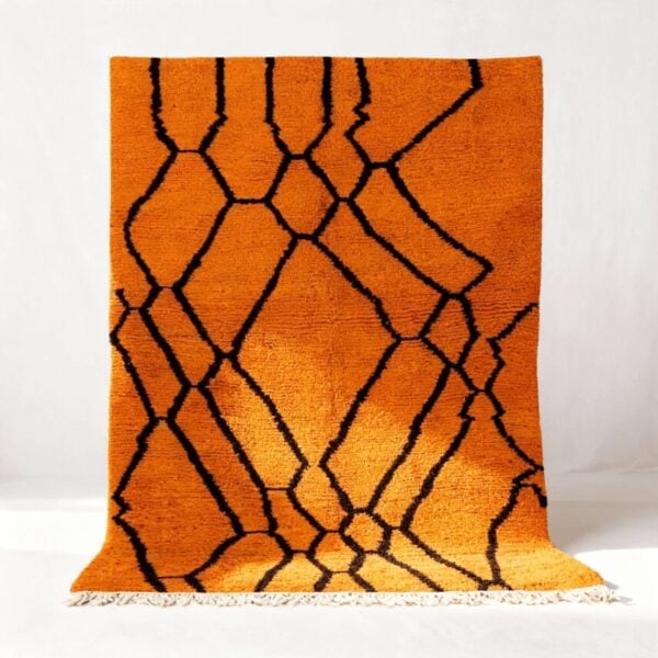 Handwoven Moroccan rug with vibrant orange wool and bold black geometric diamond pattern with white fringe trim