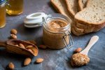 Amlou with almonds Moroccan spread in glass jar with bread and almonds on rustic wooden board for breakfast