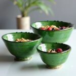 Three ceramic clay bowls filled with cereal and berries, showcasing functional handcrafted green pottery