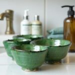 Tamegroute green ceramic clay bowls displayed in bathroom setting, showing glossy glaze and handmade pottery