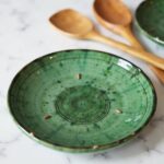 Close-up of Tamegroute pottery plates showing concentric circles, green glaze finish and amber accent details