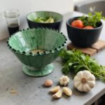 Empty green ceramic pottery bowl on pedestal base, showcasing traditional Moroccan ruffled rim design