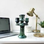 Triple arm ceramic candlestick holder in Tamegroute green displayed on white desk with brass lamp and decor