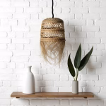 Handmade straw hanging light against white brick wall with wooden shelf