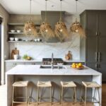 Four handwoven straw pendant lights over marble kitchen island with modern gray cabinets