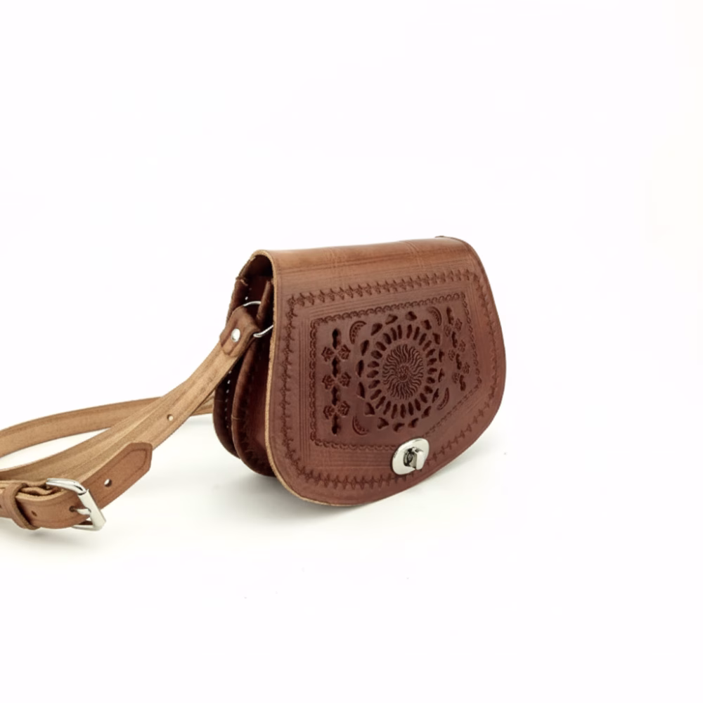 Angled view of Small leather crossbody bag with adjustable strap and embossed floral detail.