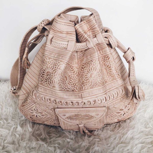 Light tan convertible leather backpack with ornate hand-tooled patterns and decorative cutout leather work