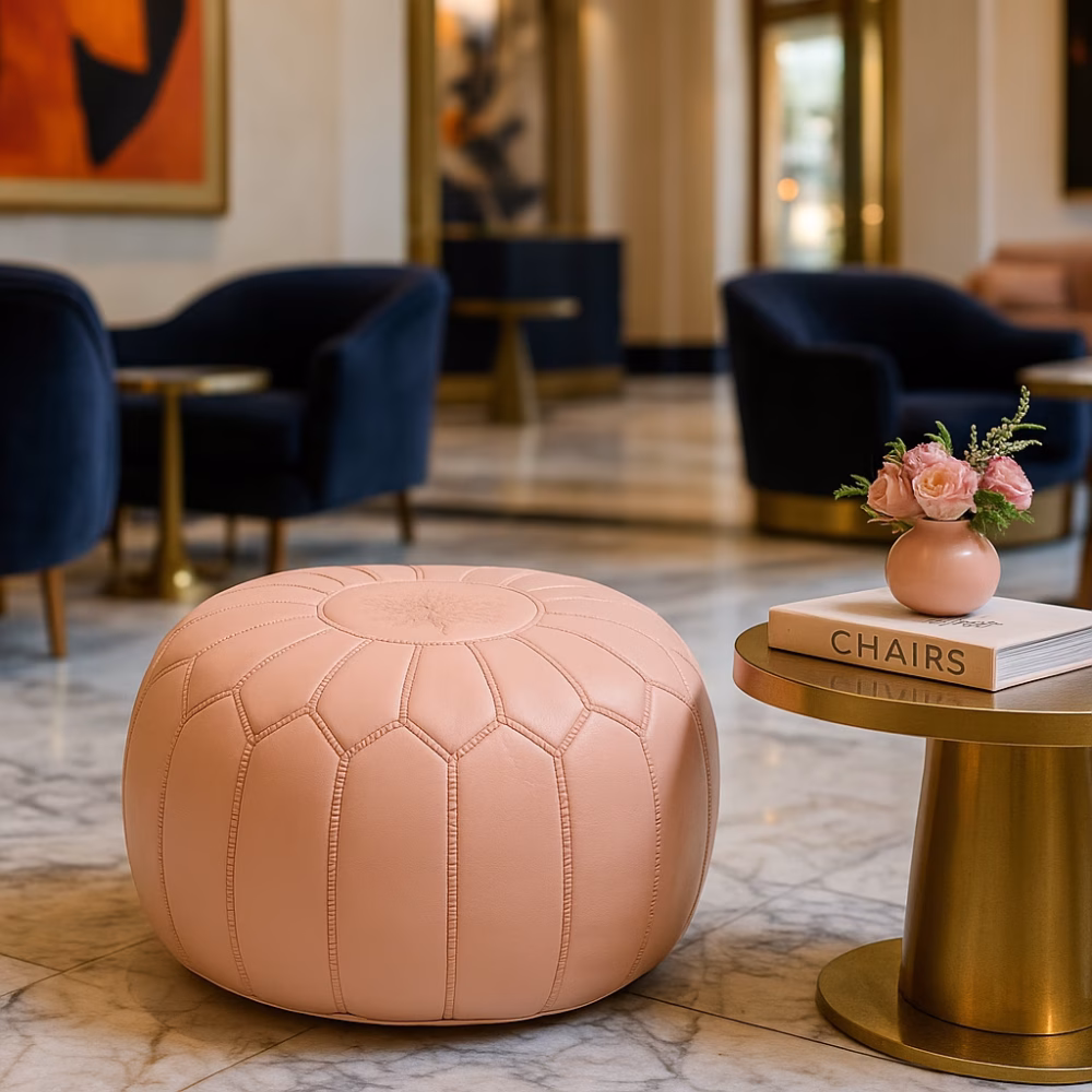 Elegant pink pouf in a luxury hotel lobby with marble floors, gold accents, and navy velvet chairs in the background.