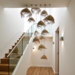 Multiple handwoven straw lighting pendants cascading down stairwell creating dramatic sculptural installation