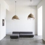 Pair of handwoven straw lighting pendants with natural texture in minimalist living room with gray sofa