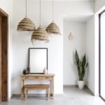 Grand handwoven straw chandelier with frayed edges above platform bed in neutral toned minimalist bedroom