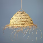 Large textured straw chandelier casting warm glow over wooden dining table