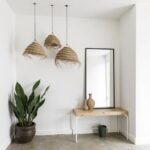 Three handwoven straw chandeliers in herringbone weave hanging over minimalist entryway console table