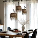 Handwoven straw pendant lights with natural fringe above dining table creating warm filtered illumination