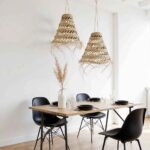 Handwoven straw pendant light with fringe casting warm shadows in sunlit room near window