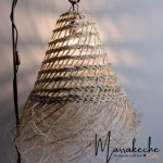 Single straw light shade against white brick wall with wooden shelf
