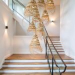 Two handwoven straw pendant lights with natural fringe above dining table in Scandinavian style room