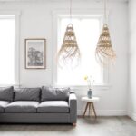 Handwoven straw pendant light pair hanging in minimalist living room with white walls and gray sofa
