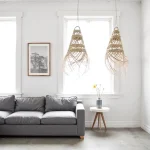 Handwoven straw pendant light pair hanging in minimalist living room with white walls and gray sofa