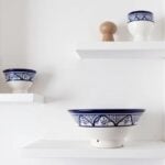 Hand-painted ceramic bowl collection on white shelves, navy blue floral patterns, artisan serving dishes
