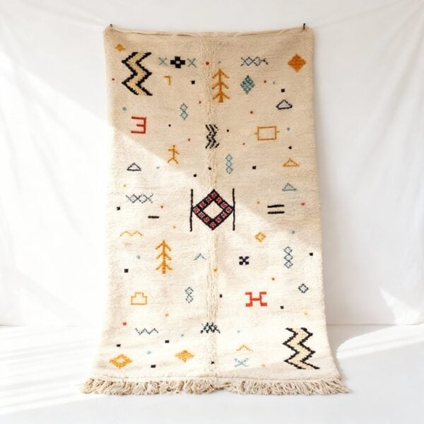 Handmade Moroccan boho rug with colorful geometric patterns on cream wool, featuring tribal symbols and fringe details