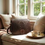 Cozy lifestyle shot of embossed leather shoulder bag on armchair with coffee cup by window