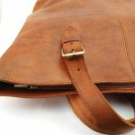 Interior of leather tote bag showing zippered pocket and suede-like lining in tan