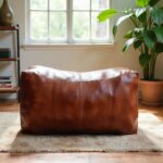 Leather rectangle ottoman 36 inch floor pouf backlit by window showing rich cognac brown leather patina