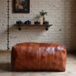 Leather rectangle ottoman 36 inch cognac brown pouf on wood floor with exposed brick wall and vintage cameras