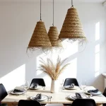 Three handwoven straw pendant lights in varied sizes with bohemian fringe detail in sunlit dining space