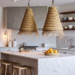 Pair of artisanal straw lamps hanging above marble kitchen island with wooden stools