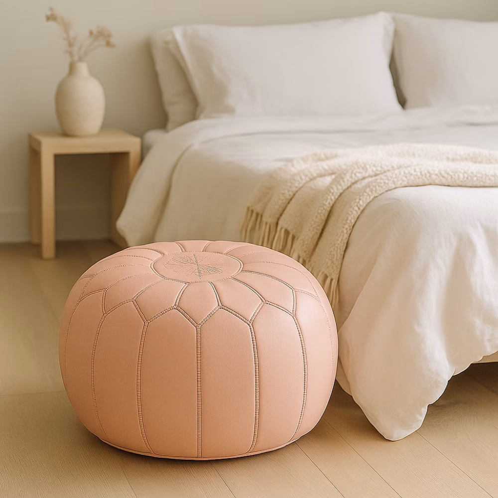 Soft pink pouf at the foot of a neatly made bed in a minimalist bedroom, paired with neutral bedding and light wood furniture.