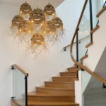 Cluster of handwoven straw pendant lights illuminated on stairway with glass railing