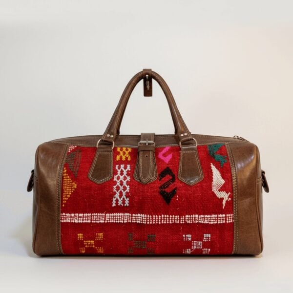 Kilim leather duffle bag with red handwoven wool panels and brown leather trim, featuring dual handles and brass hardware