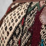 Macro close-up of the handwoven kilim wool panel showing geometric Berber diamond and chevron motifs in burgundy, cream, green, and black