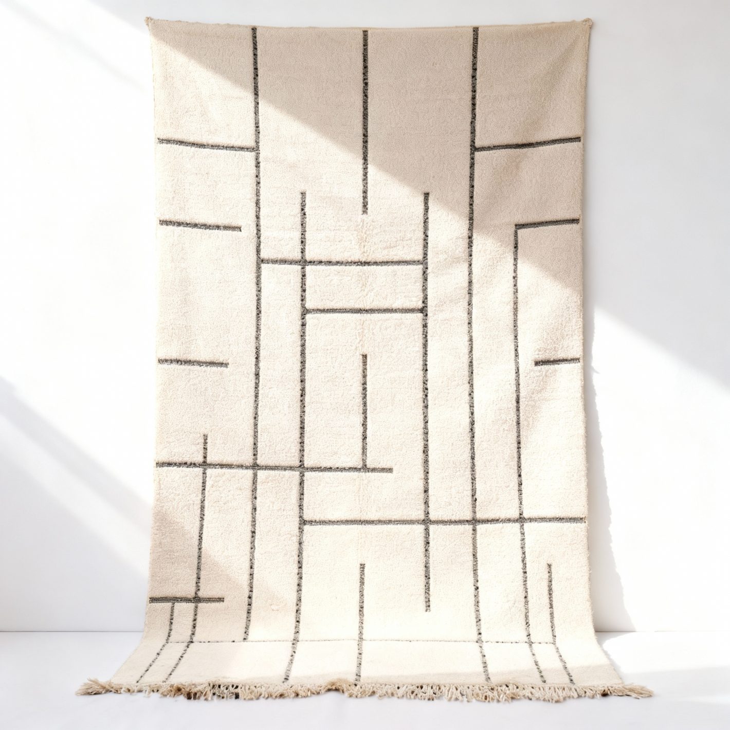 Authentic moroccan geometric rug hanging display showcasing handmade wool texture and geometric patterns (2) Handmade white Moroccan geometric rug with black lines, premium wool, 2x3m with fringe detail