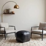 Black leather square pouf ottoman placed between neutral chairs in minimalist room setting