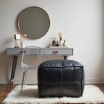 Black leather square pouf as vanity seating with clear chair at modern makeup table