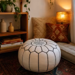 White leather pouf in a cozy reading nook with a patterned rug, soft cushions, and ambient lighting.