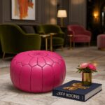 Pink leather round ottoman in luxury hotel lobby with Jeff Koons book and peonies - embroidered floor pouf